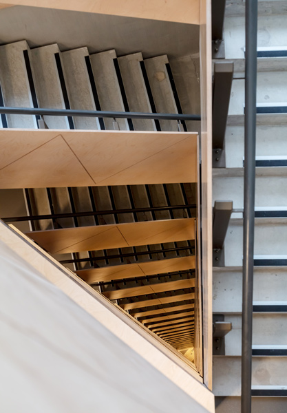 View down the stairwell showing the plywood-clad stairs and the steel balustrade, 17 of 18.